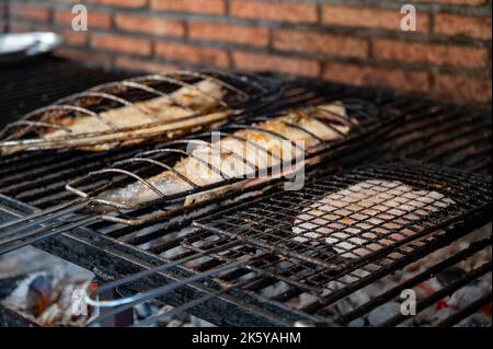 Frischer Fisch, der auf alten Kohleparrillas am Grill, weißer Fisch, Seebarsch und Steinbutt, außerhalb von Gebäuden im kleinen Fischerdorf Getaria, Baskisch, gebaut wird Stockfoto