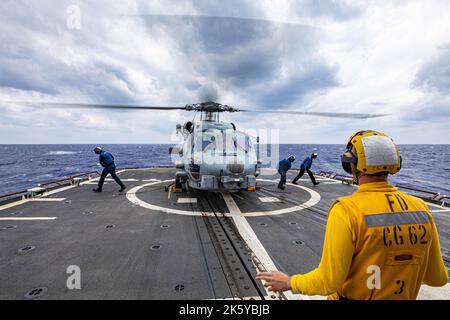 OSTCHINESISCHES MEER (OKT 10, 2022) Seeleute an Bord des Lenkraketen-Kreuzers USS Chancellorsville (CG 62) der Ticonderoga-Klasse führen am 10. Oktober 2022 Flugdecks mit einem MH-60R Hubschrauber durch, der der „SABERHAWKS“ des Hubschrauber-Seestreikgeschwaders HSM-77 im Ostchinesischen Meer zugewiesen wurde. Chancellorsville wird zur Unterstützung der Sicherheit und Stabilität im Indo-Pazifik-Raum in die US-7.-Flotte eingesetzt und ist dem Kommandanten der Task Force 70 zugewiesen, einer kampfbereiten Truppe, die das kollektive maritime Interesse ihrer Verbündeten und Partner in der Region schützt und verteidigt. (USA Navy Foto von Mass Com Stockfoto