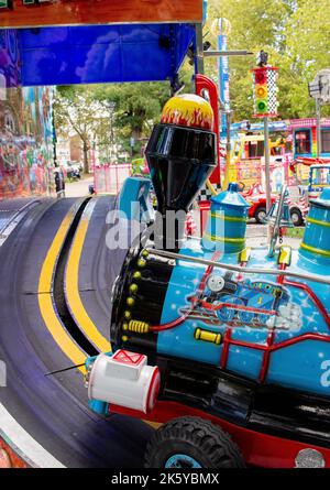 Messegelände in Parsons Green, West London, Großbritannien; Fahrgeschäfte in superhellen Farben, Luftballons, Autos, Züge und Spiderman Stockfoto