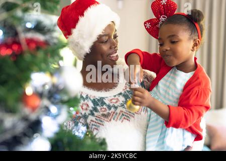 afroamerikanische Mutter und Tochter verbringen Zeit miteinander und schmücken den weihnachtsbaum Stockfoto