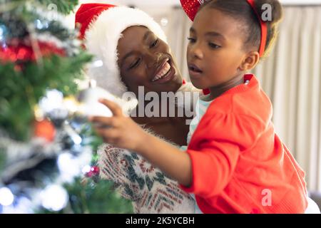 afroamerikanische Mutter und Tochter verbringen Zeit miteinander und schmücken den weihnachtsbaum Stockfoto