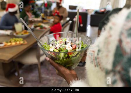 Frauen, die Salat halten, afroamerikanische Familie, die Zeit miteinander verbringen und essen Stockfoto