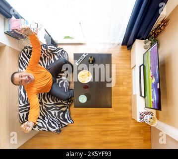 Aufgeregt Mann feiert ein Tor, während Fußball im fernsehen, Blick von oben. Stockfoto