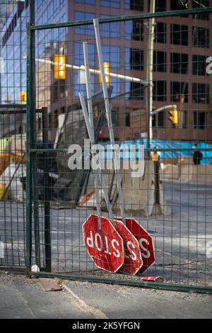 Auf dem Kopf stehende Stoppschilder, die an einem Zaun auf einer Baustelle angebracht sind Stockfoto