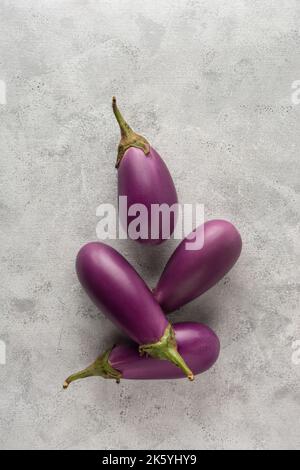 Auberginen oder brinjal, Gemüse auf weißem texturierten Hintergrund, Nahaufnahme von oben mit Kopierraum Stockfoto