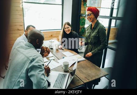 Fröhliche Geschäftsleute, die während einer Besprechung glücklich lachen. Gruppe von verschiedenen Geschäftsleuten, die kreative Ideen in einem Büro austauschen. Geschäftsmann Stockfoto