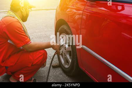 Jakarta, Indonesien 10. Oktober 2022 : Nahaufnahme Mechaniker Reifen aufblasen und Luftdruck mit Manometer Druck in der Tankstelle prüfen Stockfoto