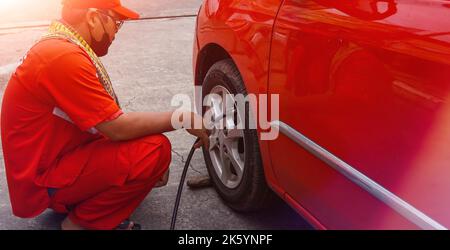 Jakarta, Indonesien 10. Oktober 2022 : Nahaufnahme Mechaniker Reifen aufblasen und Luftdruck mit Manometer Druck in der Tankstelle prüfen Stockfoto