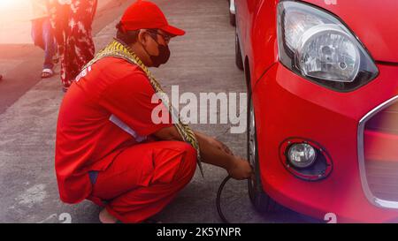 Jakarta, Indonesien 10. Oktober 2022 : Nahaufnahme Mechaniker Reifen aufblasen und Luftdruck mit Manometer Druck in der Tankstelle prüfen Stockfoto