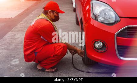 Jakarta, Indonesien 10. Oktober 2022 : Nahaufnahme Mechaniker Reifen aufblasen und Luftdruck mit Manometer Druck in der Tankstelle prüfen Stockfoto