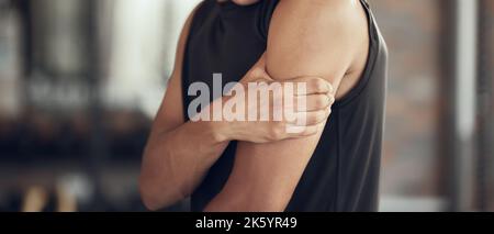 Hände eines Bodybuilders mit Armschmerzen. Fit Mann mit einem Wunde Bizeps beschnitten. Aktiver Sportler, der im Fitnessstudio seinen schmerzenden Arm berührt. Sportler mit einem verletzten Arm Stockfoto