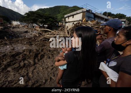 Las Tejerias, Venezuela. 10. Oktober 2022. Eine Frau schaut mit ihrer Tochter und mehreren Nachbarn auf Schäden nach Überschwemmungen und einem Erdrutsch. Nach dem Sturm 'Julia' ist die Verwüstung groß. Nach offiziellen Angaben starben in Mittel- und Südamerika insgesamt mindestens 59 Menschen an den Folgen von Stürmen und Überschwemmungen. Die Zahl der Todesopfer nach einem Erdrutsch in Venezuela ist auf mindestens 34 gestiegen. Kredit: Jesus Vargas/dpa/Alamy Live Nachrichten Stockfoto