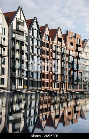 Moderne Gebäude über dem Fluss Motlawa in der Altstadt. Abstrakte Struktur. Kreatives Foto Tourismus auf dem Motlawa River. Neue Apartments-Architektur auf Granary Island Glasfenster mit Reflexionen. Touristisches Reiseziel Stockfoto