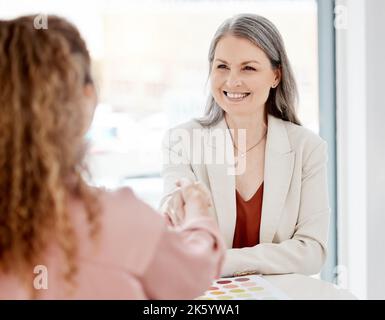 Zwei kaukasische Geschäftsfrauen, die sich bei einem Treffen bei der Arbeit die Hände schüttelten. Geschäftsleute begrüßen sich gegenseitig und machen Geschäfte miteinander. Reife weibliche Chefin Stockfoto