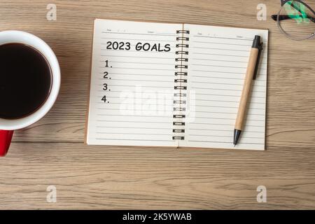 2023 TOR mit Notizbuch, schwarzer Kaffeetasse und Stift auf Holztisch, Draufsicht und Kopierfläche. Frohes neues Jahr, Auflösung, To-Do-Liste, Strategie und Plan CO Stockfoto