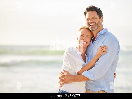 Nahaufnahme eines reifen, liebevollen kaukasischen Paares, das am Strand steht und während des Sonnenuntergangs im Freien lächelt. Kaukasisches Paar, das Liebe zeigt Stockfoto