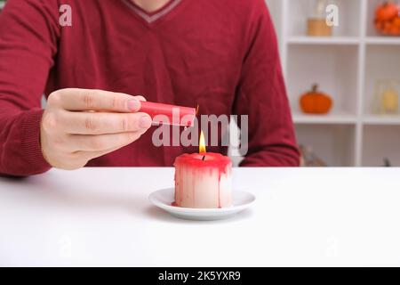 DIY Halloween Halloween weiße Kerze, bedeckt mit rotem Wachs wie Bluttropfen auf weißem Hintergrund. Geschenkidee, Dekor Halloween. Schritt für Schritt. Blutige Kerzen für Halloween-Urlaub. Workshop. Stockfoto