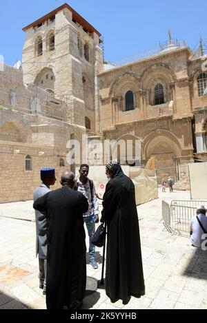 Koptische Priester stehen im Hof der Kirche des heiligen Grabes in der Altstadt von Jerusalem. Stockfoto