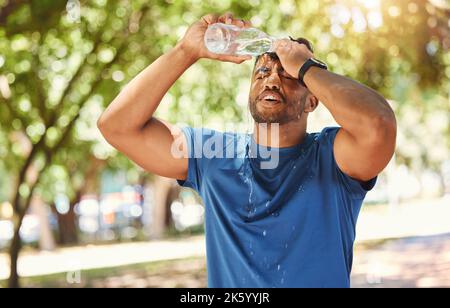 Junger, gemischter Athlet, der seinen Kopf mit Wasser bespritzt und hydratisiert bleibt, während er sich auf Gesundheit und Fitness konzentriert. Durstiger Mann, der eine Pause von nimmt Stockfoto