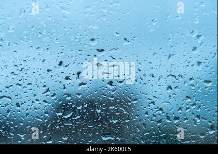 Wassertropfen auf das Fensterglas. Regentropfen auf dem Fenster. Blauton. Regentropfen auf Glas. Abstrakter tropfenweise Regen Hintergrund Stockfoto