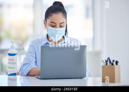 Geschäftsfrau mit Laptop, während der Covid mit Maske und Händedesinfektionsmittel für Hygiene und Gesundheit. Junge Unternehmensfachkraft, Sicherheit und Hygiene Stockfoto