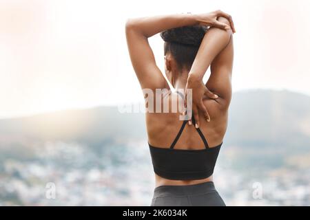 Rückansicht einer jungen afroamerikanischen Athletin, die beim Stretching vor dem Training im Freien einen Blick auf den Blick hat. Engagierte schwarze Frau Stockfoto