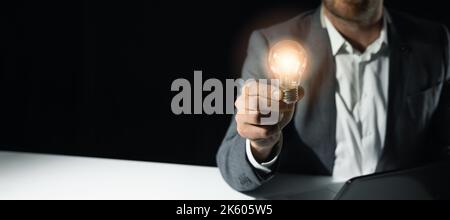 Geschäftsmann hält Glühbirne in der Hand. Business-Lösungen, Startup und neue Idee Konzept. Banner mit Kopierraum Stockfoto