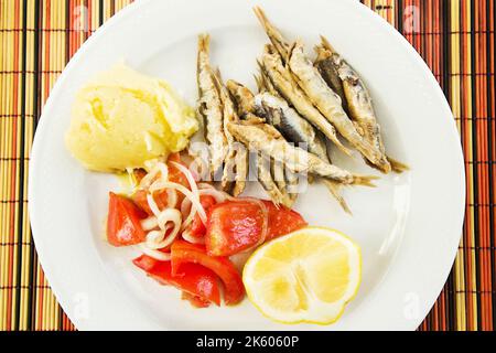 Frittierter Whitebait mit einer Seite Kartoffelpüree und Tomatensalat (selektiver Fokus) Stockfoto