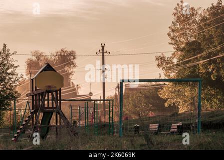 Babyschaukeln auf dem Spielplatz bei bewölktem Wetter Sonnenaufgang Morgennebel leer verlassene Kinder Spielplatz Rutschen und Schaukeln nebliger Herbst ländliche Olanesti Stockfoto