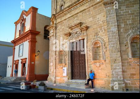 Ein älterer Mann, der vor der Kirche San Domenico al Rosario in der Altstadt von Gallipoli, Apulien (Apulien), Italien, bei warmem Abendsonne steht. Stockfoto