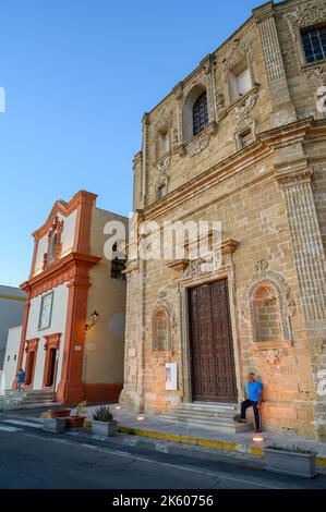 Ein älterer Mann, der vor der Kirche San Domenico al Rosario in der Altstadt von Gallipoli, Apulien (Apulien), Italien, bei warmem Abendsonne steht. Stockfoto