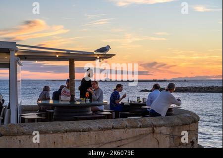 Menschen, die Speisen und Getränke im Freiluftrestaurant Buena Vista am mittelalterlichen Stadtwall am Meer in der Altstadt von Gallipoli, Apulien (Apulien), Italien, genießen. Stockfoto