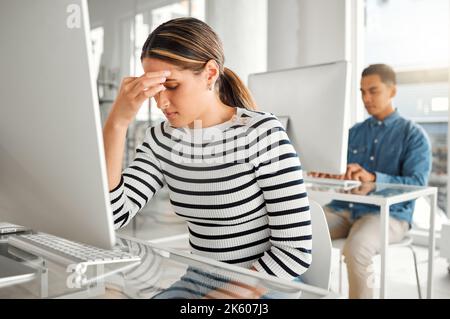 Junge gestresste Geschäftsfrau mit gemischter Rasse, die bei der Arbeit an einem Desktop-Computer unter Kopfschmerzen leidet. Eine unglückliche hispanische Frau Stockfoto