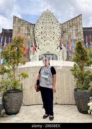 Kuta, Indonesien. 10. Oktober 2022. Thiolina Marpaung steht vor dem Denkmal für die Opfer der Angriffe von Bali am 12. Oktober 2002. Auf einer Tafel sind die Namen der 202 Opfer aufgeführt. Die Indonesierin überlebte den Angriff schwer verletzt und verlor fast ihr Sehvermögen. Heute setzt sie sich dafür ein, dass die Opfer nicht vergessen werden. Quelle: Carola Frentzen/dpa/Alamy Live News Stockfoto