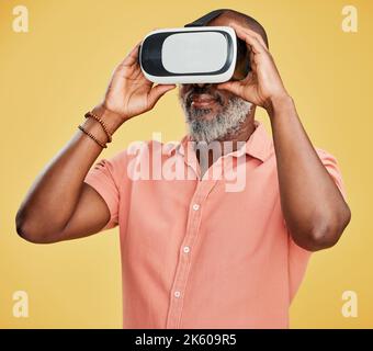 Ein reifer afroamerikanischer Mann, der ein Virtual-Reality-Headset verwendet, während er isoliert vor einem gelben Hintergrund im Studio steht. Schöner Mann mit einem Stockfoto