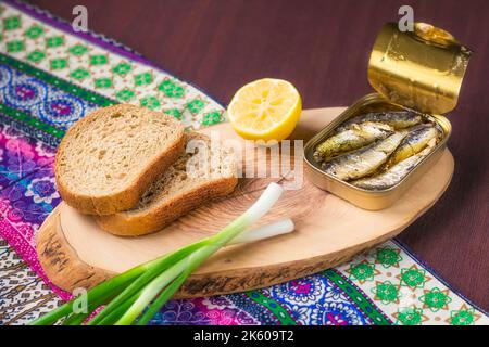 Eine Dose Sardinen serviert mit Vollkornbrot, Zwiebeln und Zitrone (selektiver Fokus) Stockfoto