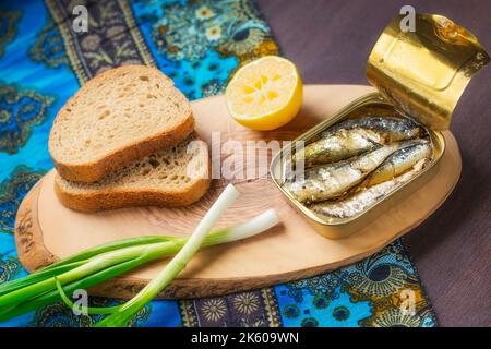 Eine Dose Sardinen serviert mit Vollkornbrot, Zwiebeln und Zitrone (selektiver Fokus) Stockfoto