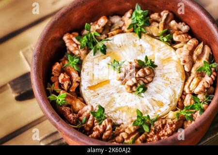 Gebackener Brie-Käse mit Honig, Walnüssen und Thymian (selektiver Fokus) Stockfoto