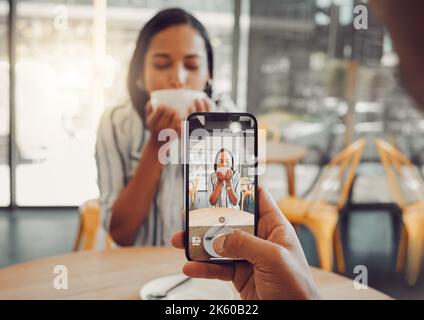 Nahaufnahme des Gerätebildschirms, während Sie eine schöne junge Frau beim Kaffeetrinken und Date im Café genießen. Mann, der Mobiltelefon hält und nimmt Stockfoto