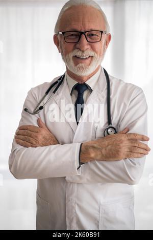 Bild eines professionellen Mediziners, der eine Brille und ein Stethoskop trägt und für die Kamera lächelt. Stockfoto