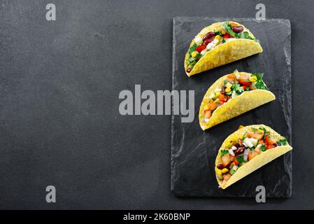 Mexikanische Tacos mit Gemüse auf dunklem Hintergrund auf Schiefer. Leerer Raum für Text Stockfoto