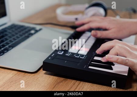 Midi Keyboard Musiker spielt Midi Keyboard für das Arrangieren von Musik auf Laptop-Computer Musik Produktion Technologie Konzept Stockfoto