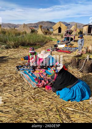 Frauen der Uru- oder Uros-Völker, Ureinwohner Perus und Boliviens, während sie mit Stoffstücken auf ihrer schwimmenden Insel im Titicacasee arbeiteten. Stockfoto