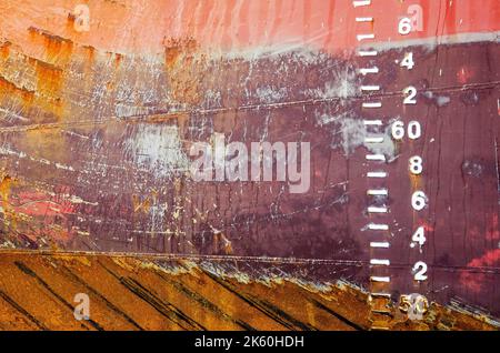 Farbenfrohe Muster aus Rost, Schmutz und Kratzern sowie die eingeprägten Zugspuren auf dem Rumpf eines alten Schiffes Stockfoto