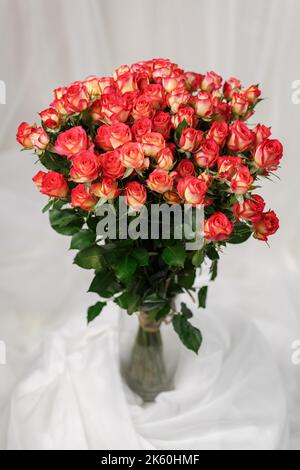 Bouquet bestehend aus vielen rosa Rosen mit hohem Stiel und der auf Ständer in Glasvase steht. Festlicher Rosenstrauß in transparenter Vase auf Backgrou Stockfoto