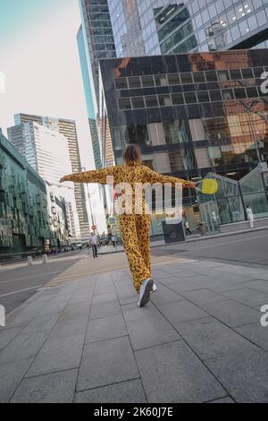 Ein Porträt einer in Mode gekleideten glücklichen Frau, die für ein Fotoshooting auf der Straße posiert Stockfoto