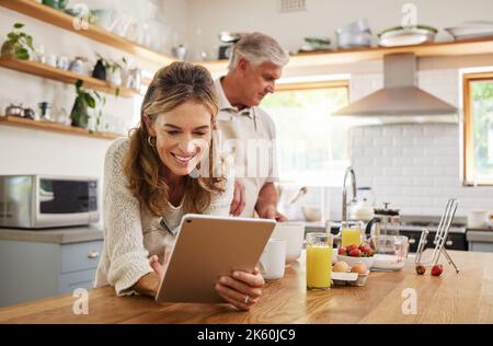 Frau, Tablet und altes Paar in der Küche zu Hause in sozialen Medien, im Internet surfen oder Nachrichten lesen. Ruhestand, älterer Ehemann und Ehefrau im Haus mit 5G Stockfoto