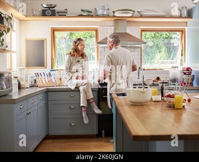 Beim gemeinsamen Kochen des Frühstücks sind Liebe und ältere Paare während des Ruhestands glücklich in ihrer Küche. Reifer Mann und Frau, Kommunikation und Entspannung Stockfoto