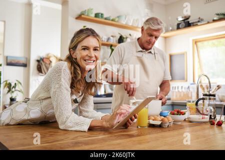 Kochen, Tablet und ältere Paare lesen Informationen über das Essen zum Frühstück im Internet in der Küche. Porträt eines älteren Mannes und einer älteren Frau mit Stockfoto