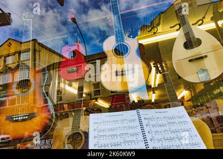 Musikinstrumente und Notenbuch im Window of Variety Sounds Irish Music Store , Killarney, County Kerry, Irland. Gitarren und Mandoline. Stockfoto